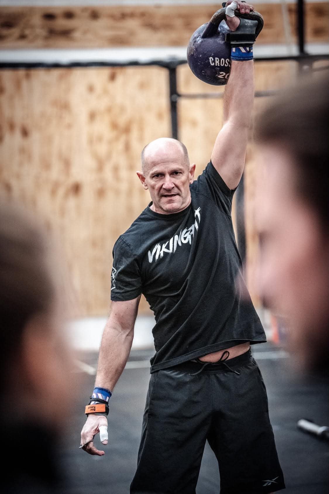Mand løfter en kettlebell over hovedet